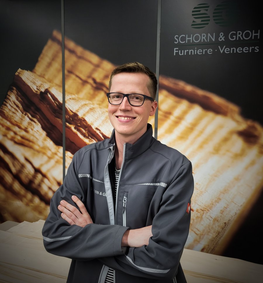 Leo Weyherter, young professional at Schorn & Groh, smiling with a backdrop of wood veneers